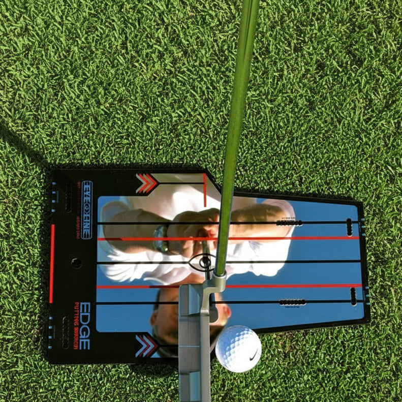 A golfer using the EDGE Putting Mirror, which is a flat, rectangular mirror with alignment lines and a built-in gate drill, placed on the green grass.